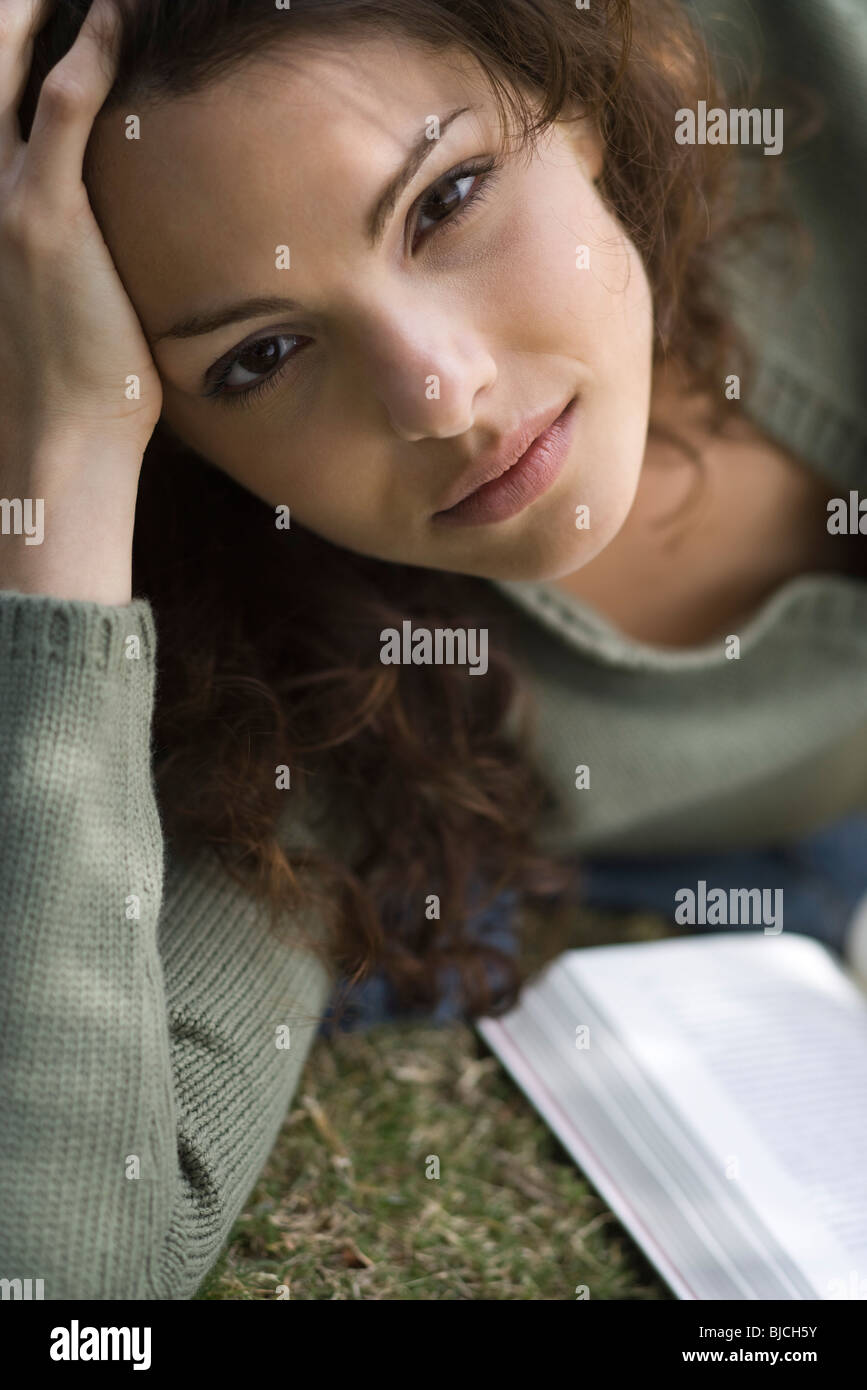 Junge Frau auf Boden liegend mit Buch, Porträt Stockfoto