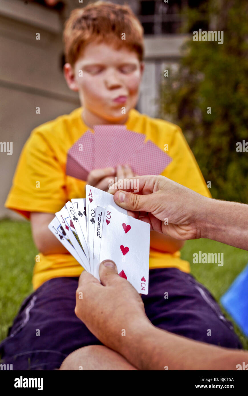 Ein zehn-jährige kaukasische rothaariger Junge wertet seine Hand, wie er Karten im Freien in Laguna Niguel, CA spielt. Stockfoto
