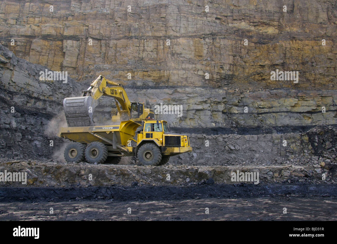 Bagger CAT 375 und Volvo Muldenkipper. schwere Maschinen, die auf einem Tagebau Baustelle Abraum aus der Kohleschicht entfernen Stockfoto