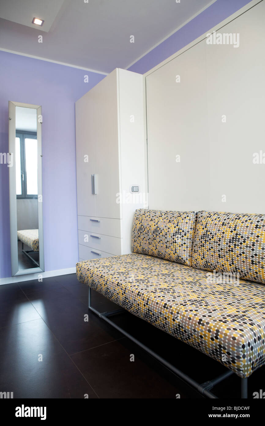 Detail aus einem Studio-Apartment mit Kleiderschrank Sofa und Murphy-Bett versteckt hinter weißen Wand Stockfoto