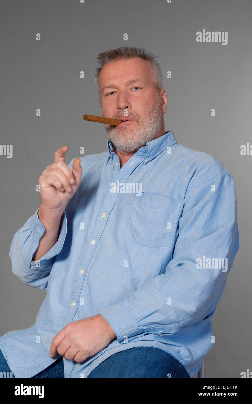 Studioportrait von einem mittleren Alter Mann im Hemd mit einer Zigarre Stockfoto