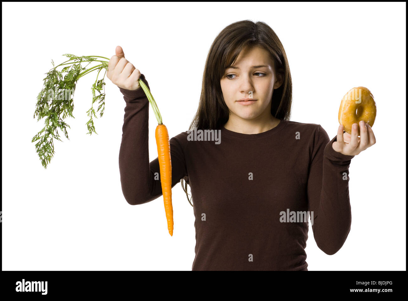 junge Frau die Wahl zwischen einer Karotte und einen donut Stockfoto