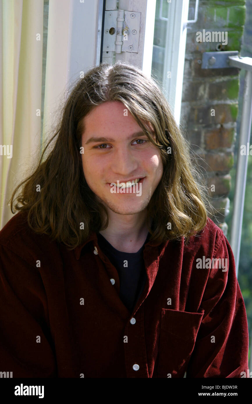Junger Mann mit langen braunen Haaren glücklich Blick in die Kamera Lächeln, Porträt Stockfoto