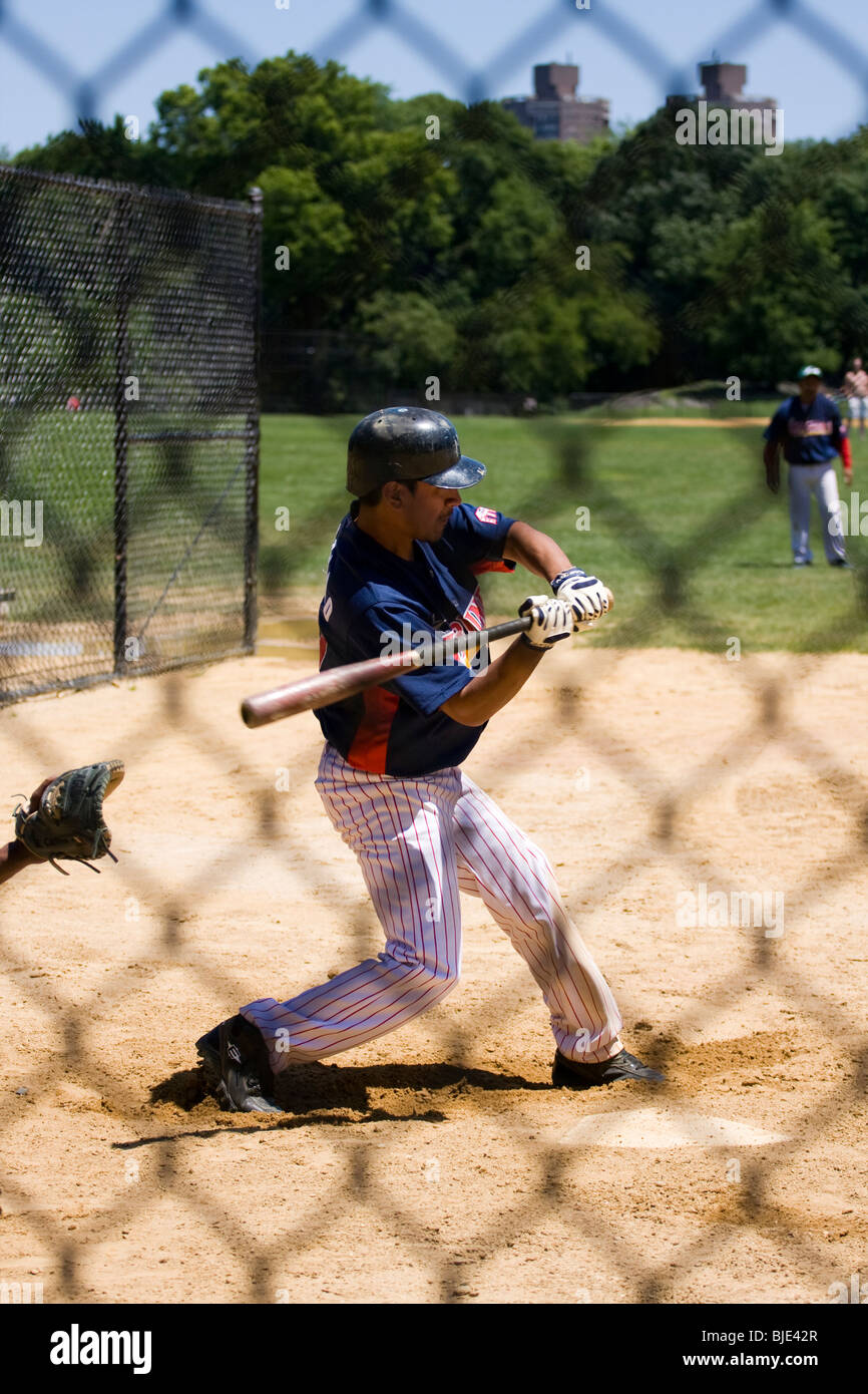 Baseball-Spieler bei Home-Plate, eine Fledermaus zu schwingen.  Schuss von hinten ein Maschendrahtzaun. Stockfoto