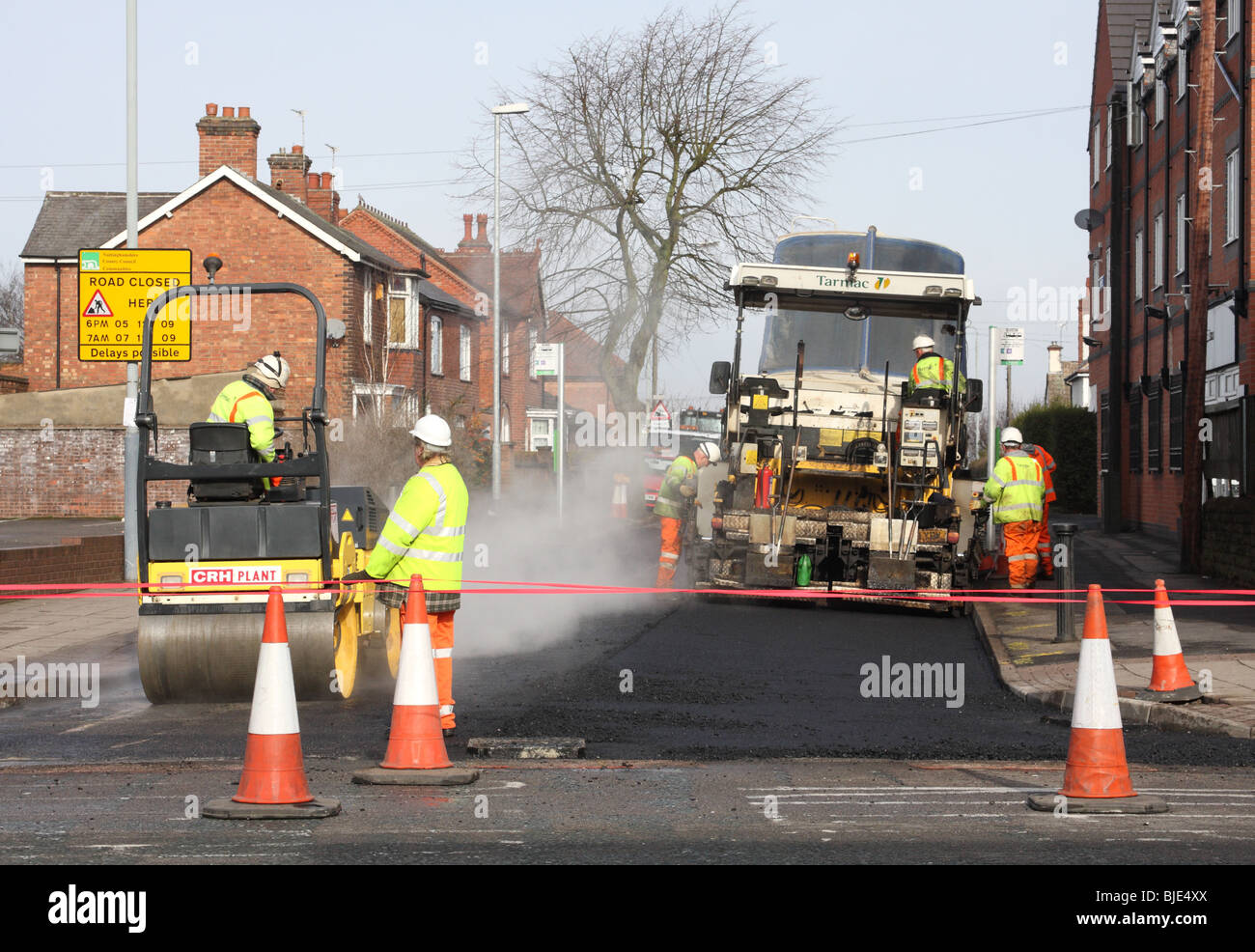 Arbeitnehmer, die Weiterleitung von Asphalt auf einer Straße in Großbritannien. Stockfoto