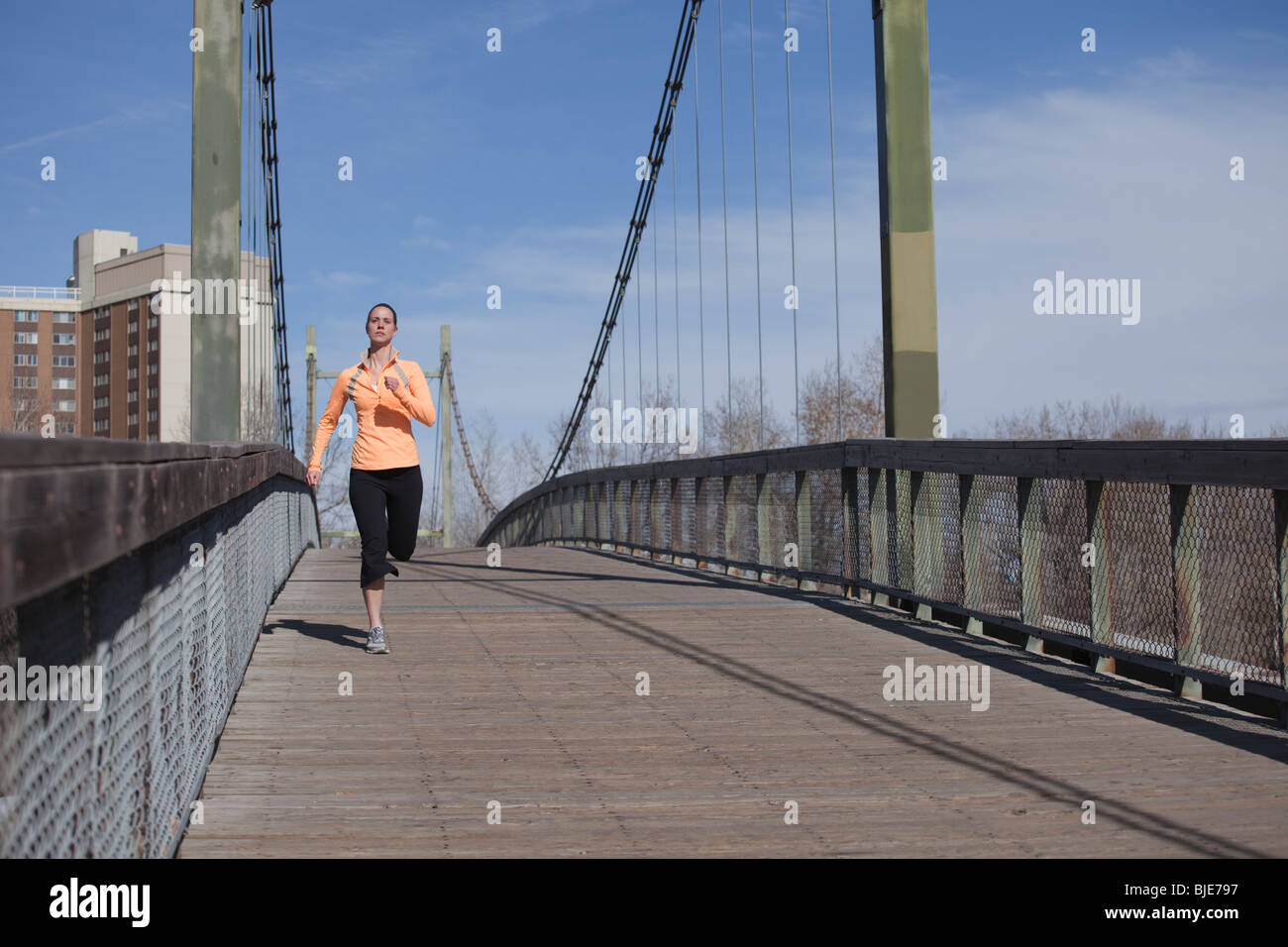 Frau läuft über Stadtbrücke Stockfoto