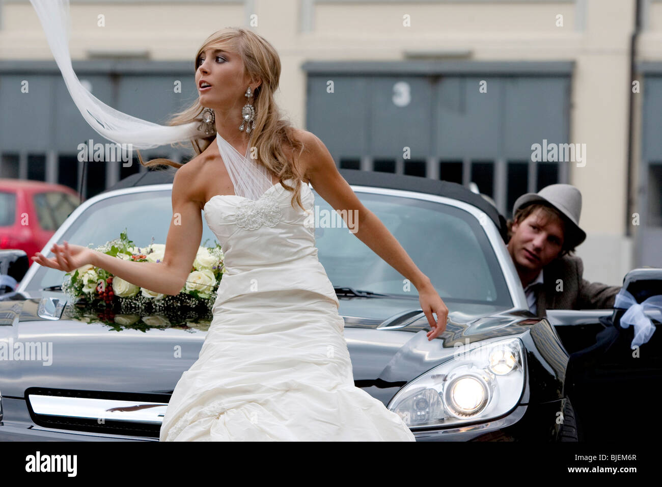 Braut vor einem Auto Bräutigam im Hintergrund Stockfoto