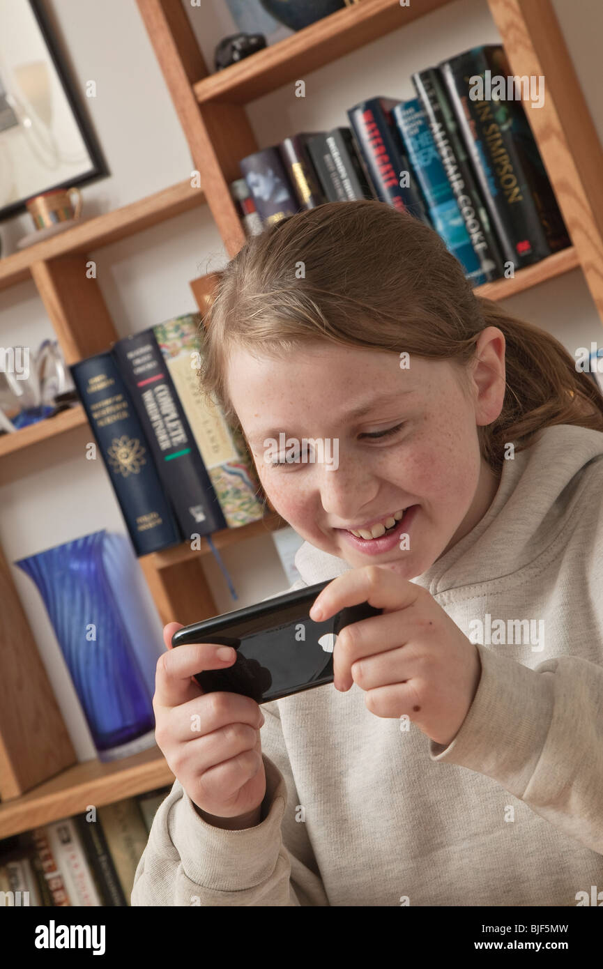 Kleines Mädchen im Alter von zehn Spielen elektronische Spiel auf dem Apple iPhone. Stockfoto