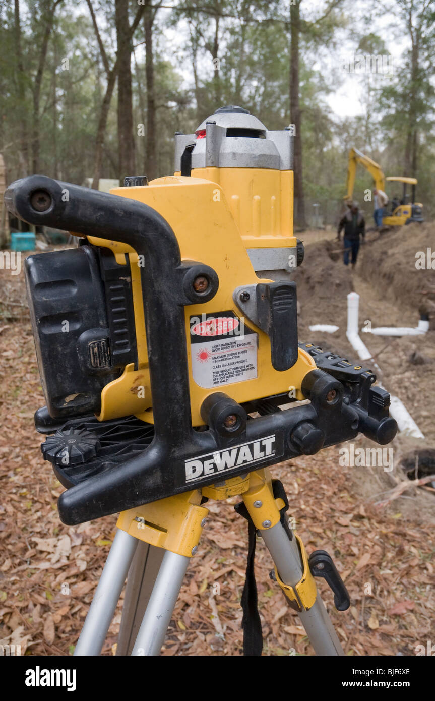 Installation von neuen septischen System Drainfield Überprüfung Ebene Winkel für die ordnungsgemäße Entwässerung mit DeWalt Laser-Wasserwaage auf einem Stativ Stockfoto