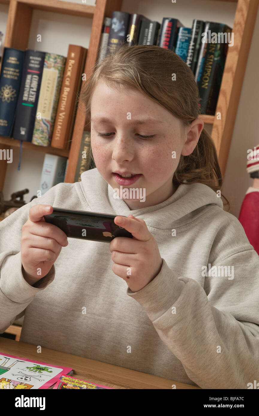 Kleines Mädchen im Alter von zehn Spielen elektronische Spiel auf dem Apple iPhone. Stockfoto