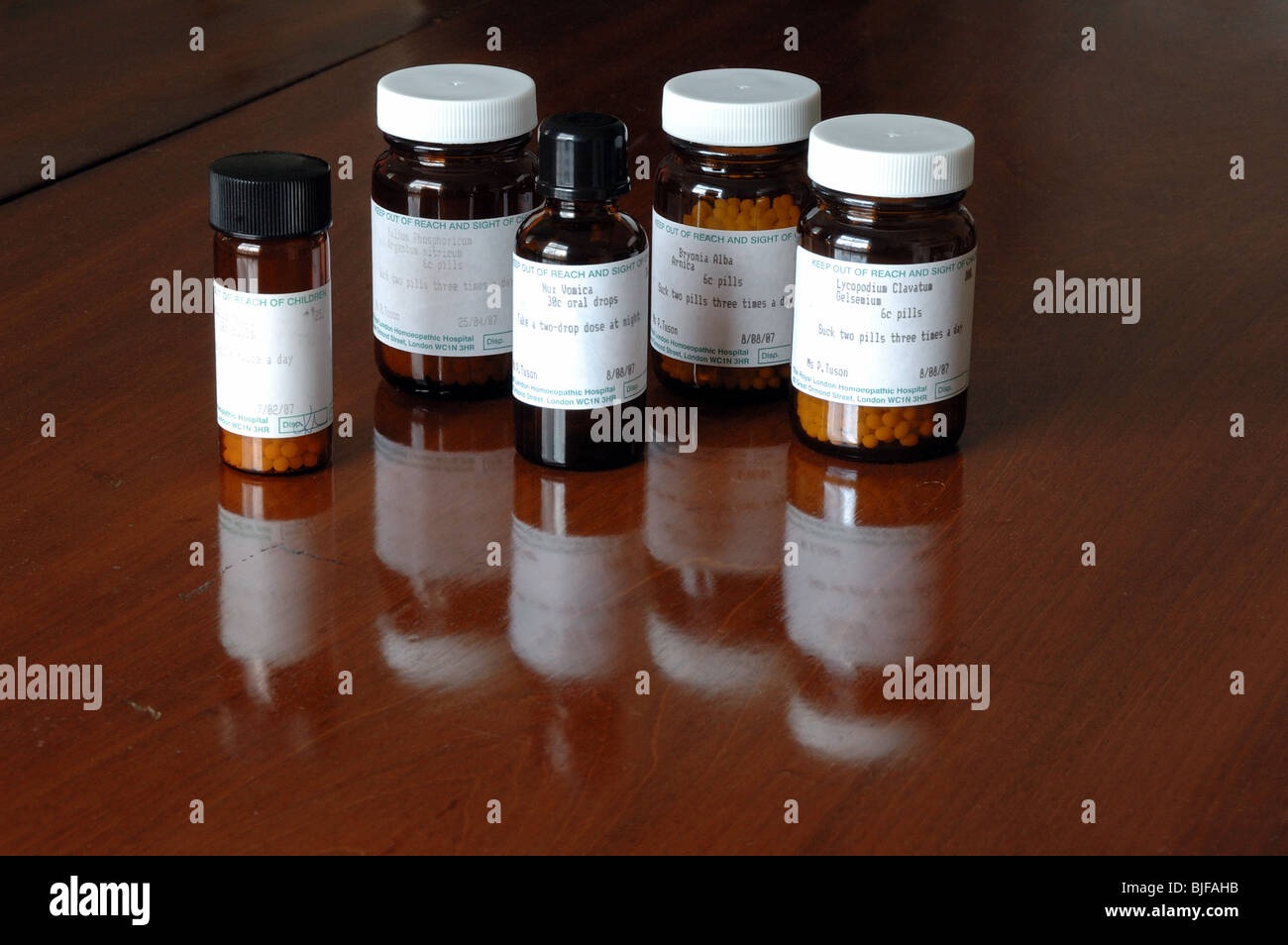 Tägliche Dosis - Flaschen homöopathische Pillen mit Schatten auf ein alter Tisch. Tabletten aus dem königlichen Londoner homöopathischen Krankenhaus UK Stockfoto