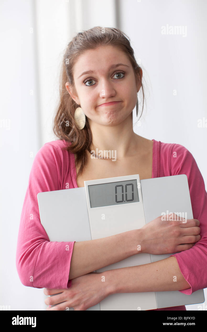 Teenager-Mädchen Carryiong einer Skala und wundern sich über ihr Gewicht Stockfoto