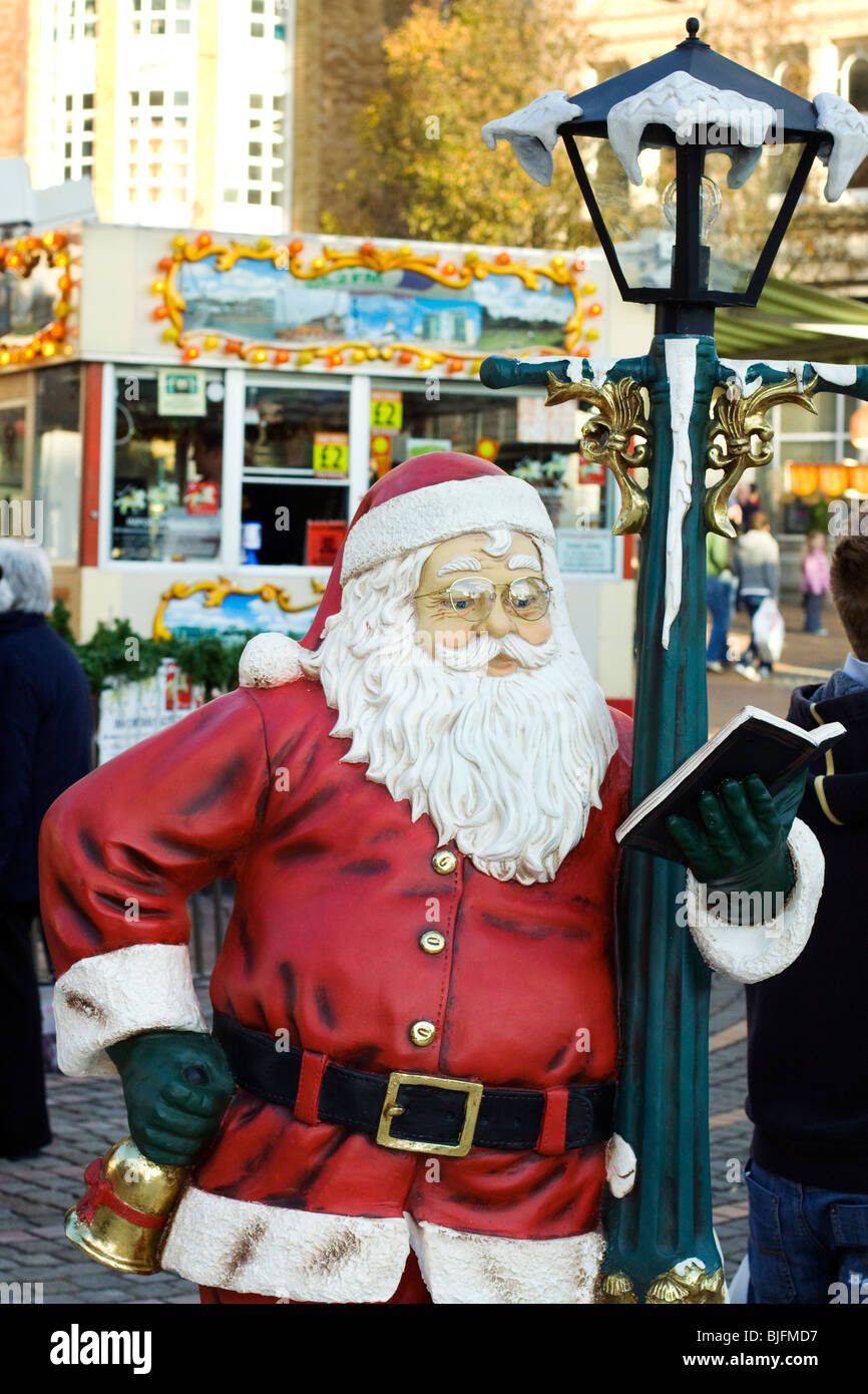 Weihnachtsmann Figur lehnt sich an einen Laternenpfahl Lesen eines Buches auf den Straßen von Bournemouth, England Stockfoto