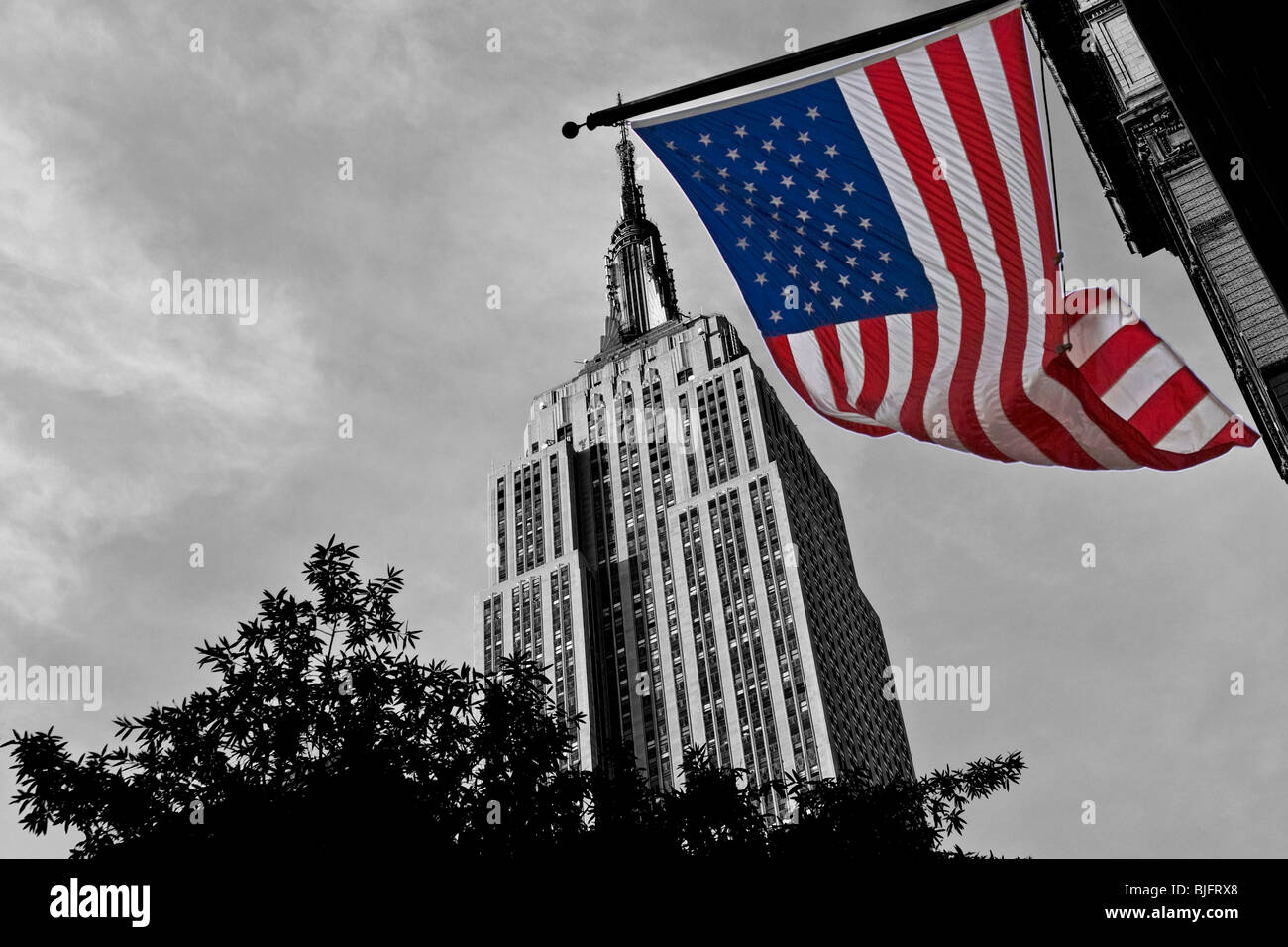 Empire State Building in New York in schwarz und weiß mit Stars And Stripes im Vordergrund in Farbe - September 2009 Stockfoto