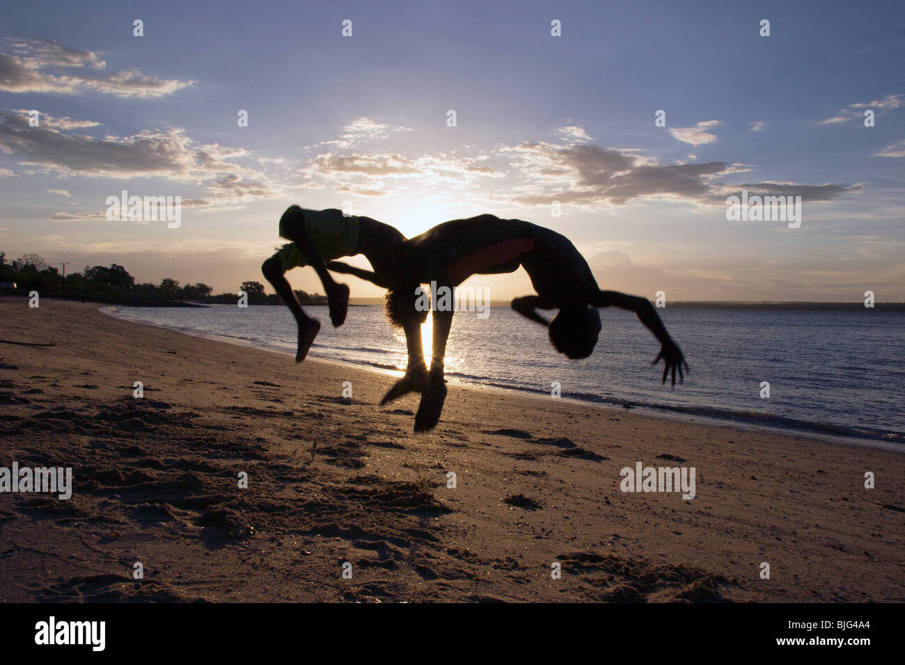Aborigines Jungs spielen und Salto am Strand bei Sonnenuntergang wo Arnhem Land Stockfoto
