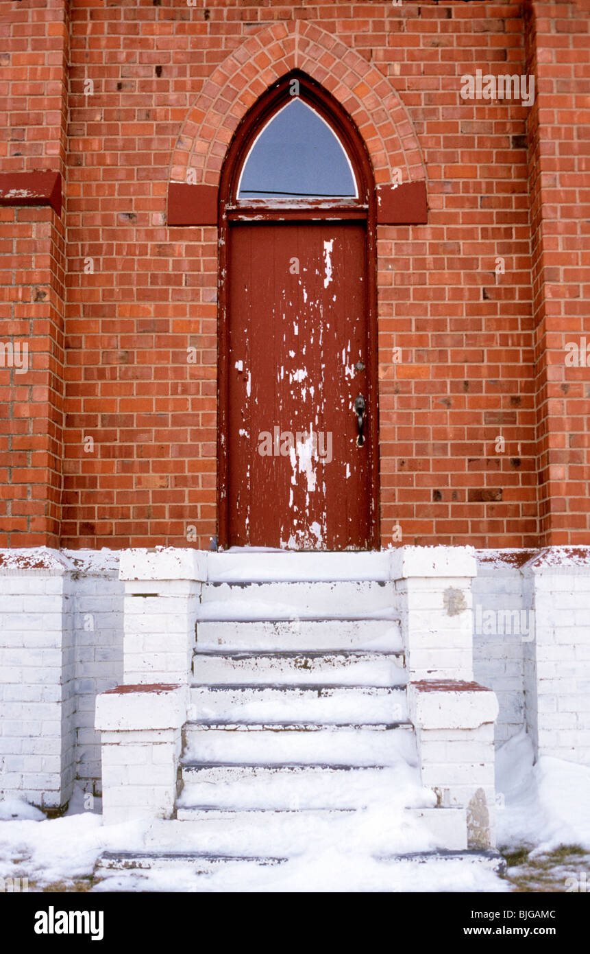 Eine rote verwitterte Kirchentür. Schuss auf Velvia-Film von der öffentlichen Straße. Stockfoto