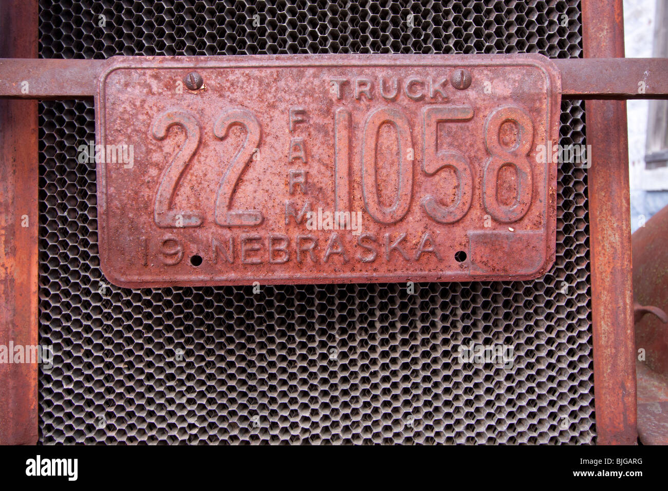 Eine verrostete Bauernhof-Kfz-Kennzeichen auf einem Rost, Oldtimer in Nebraska, USA. Stockfoto