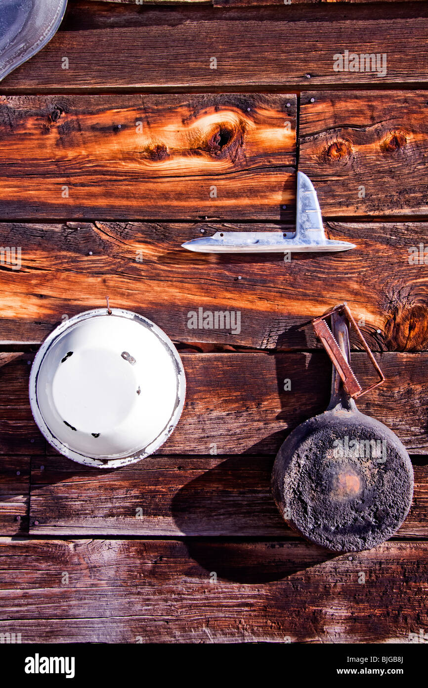 Töpfe, Pfannen und verschiedene Werkzeuge hängen an der Außenwand eine Holzhütte in Guffey, Colorado, USA. Stockfoto