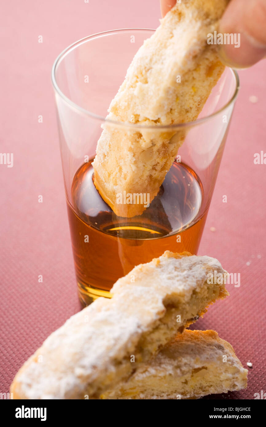 Hand eintauchen Cantucci (italienisches Mandel Keks) in Glas Vin Santo- Stockfoto