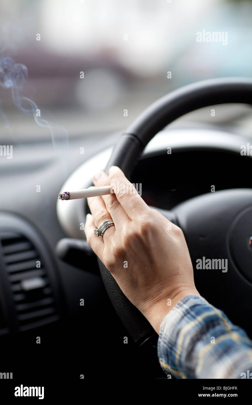 Frau Rauchen Zigarette im Auto. Ärzte in Großbritannien fordern ein Verbot des Rauchens in Autos. Stockfoto