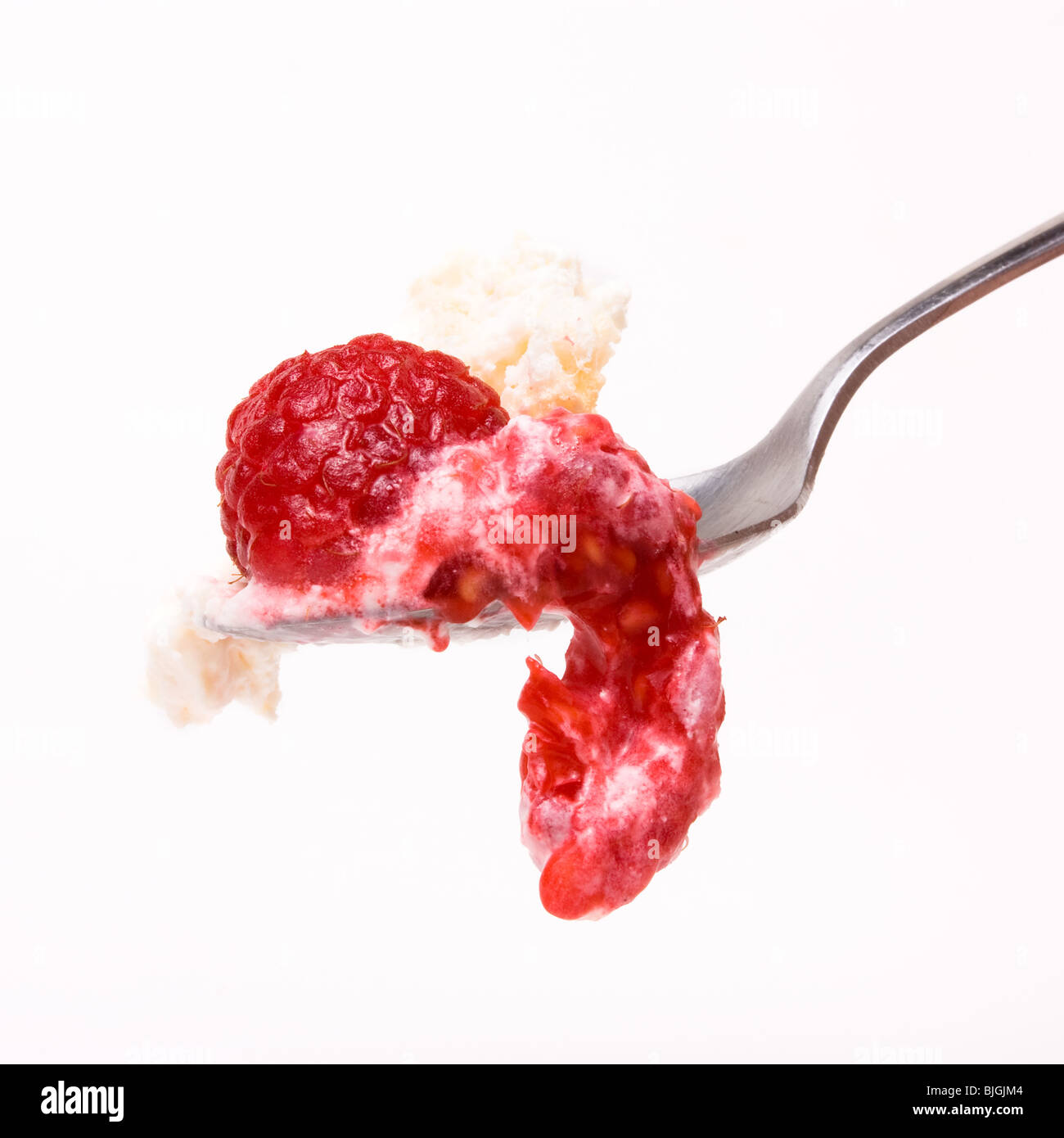 Himbeeren und Sahne tropft aus Löffel auf weißen Hintergrund isoliert. Stockfoto