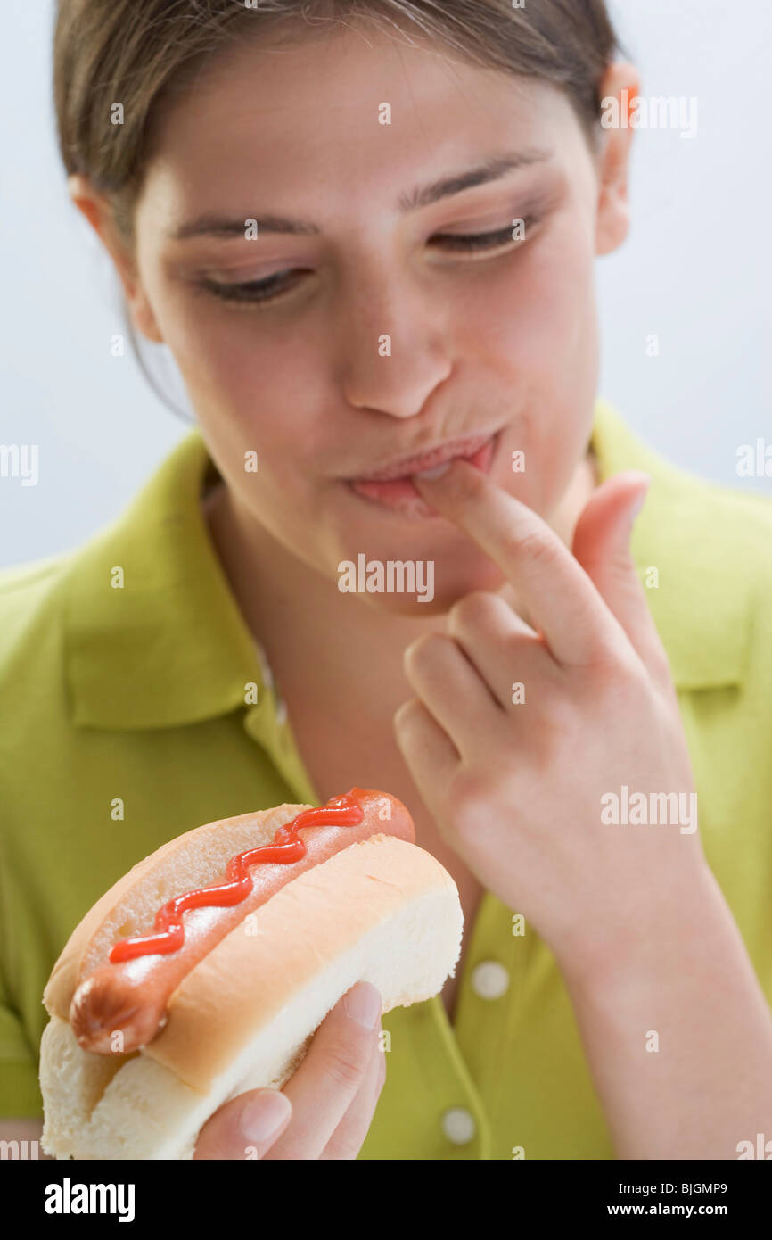 Junge Frau Verkostung Ketchup auf Hot-Dog- Stockfoto