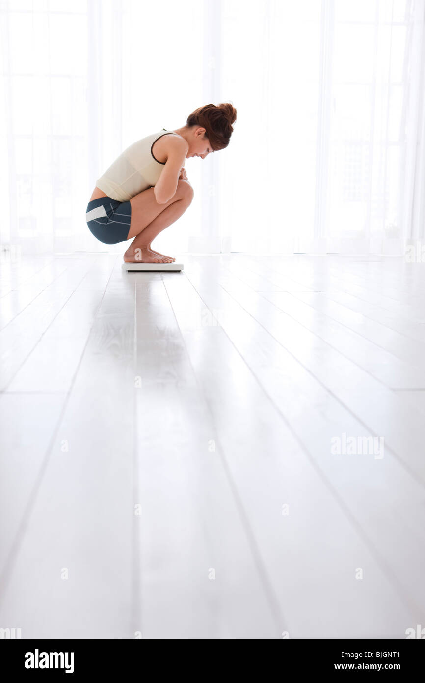Frau, die sich auf Personenwaage wiegen Stockfoto