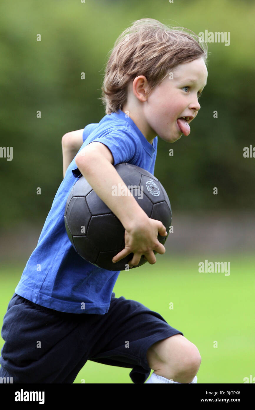 Junge läuft mit einem Fußball Stockfoto