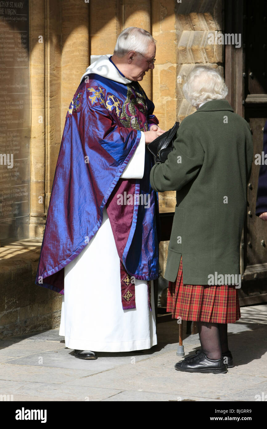 Menschen verlassen den sonntäglichen Gottesdienst in Sherborne Abbey wird durch den Pfarrer für Ihr kommen zum Anhören seiner Predigt dankte. Stockfoto