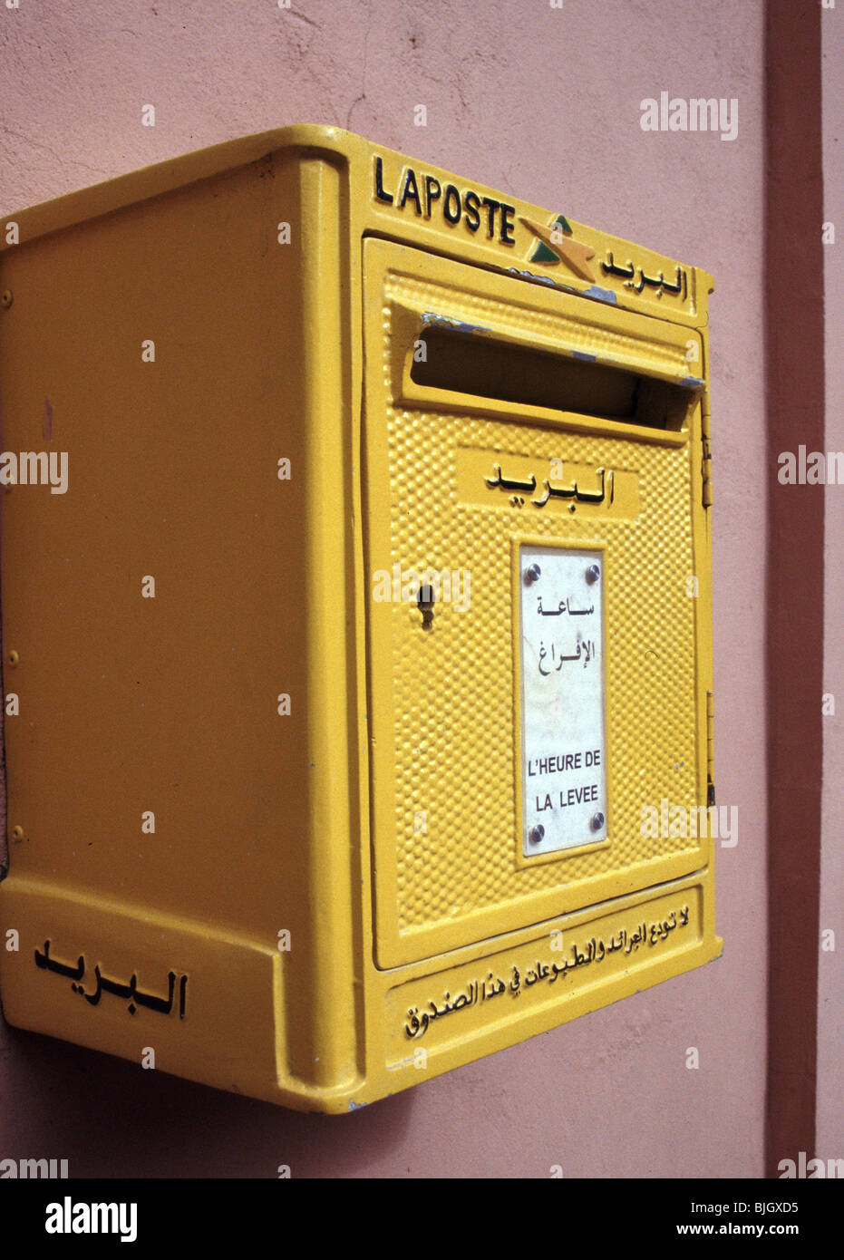Ein gelber Briefkasten an der La Poste du Maroc, Marokko, Afrika, mit dem Schreiben in Französisch und Arabisch. Stockfoto