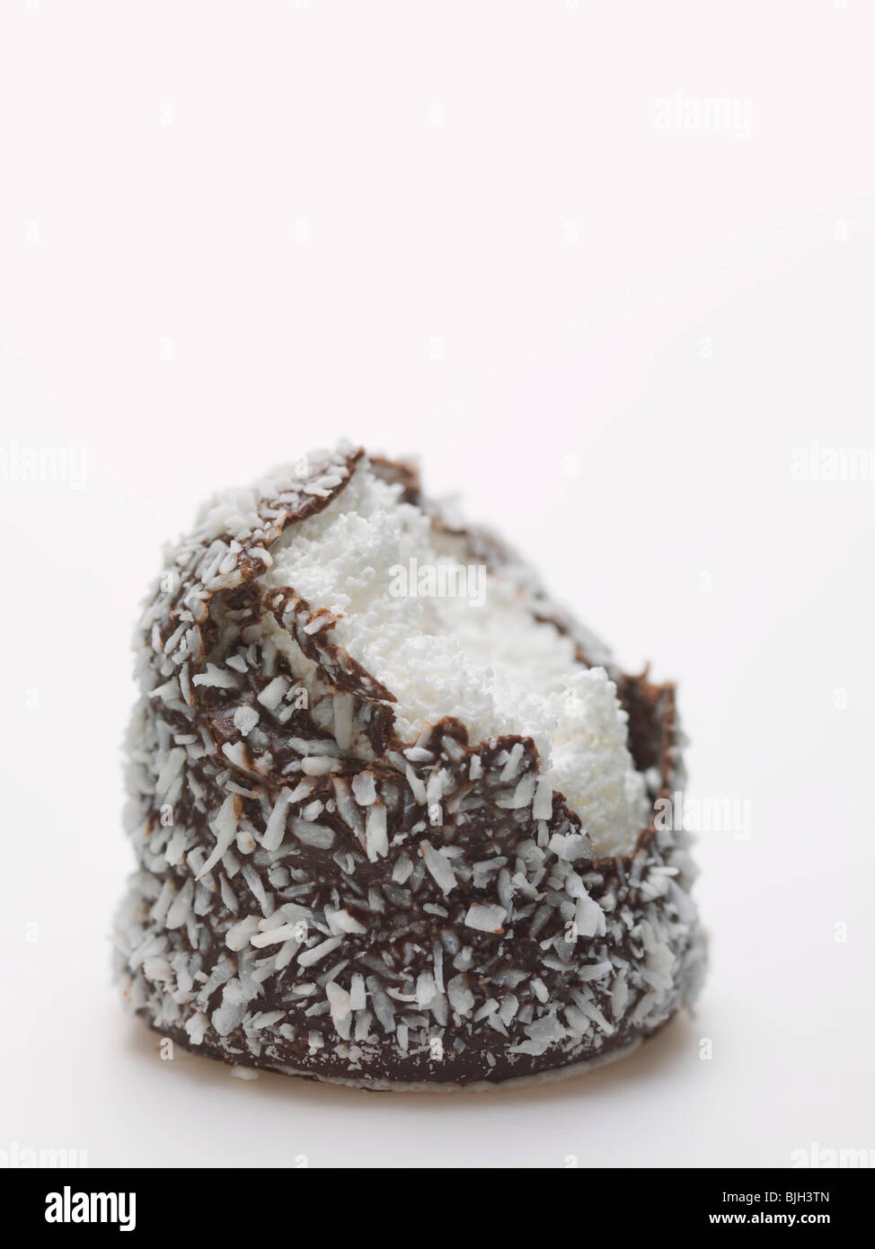 Schokolade Teekuchen bedeckt in Kokosraspeln, einen Bissen genommen- Stockfoto