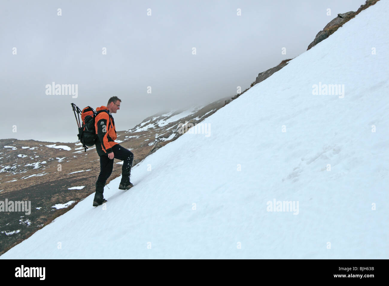 Einsamer Wanderer steigt Schnee-beklebt Cadair Idris über die steilen und instabilen Fox Weg, Snowdonia-Nationalpark, Gwynedd, Wales, UK Stockfoto