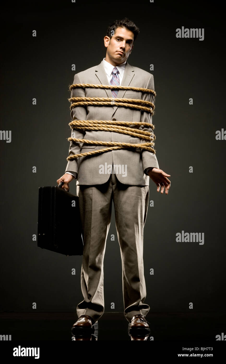 Geschäftsmann in einem vollen Anzug gefesselt mit einem Seil um seine Mitte Abschnitt Stockfoto