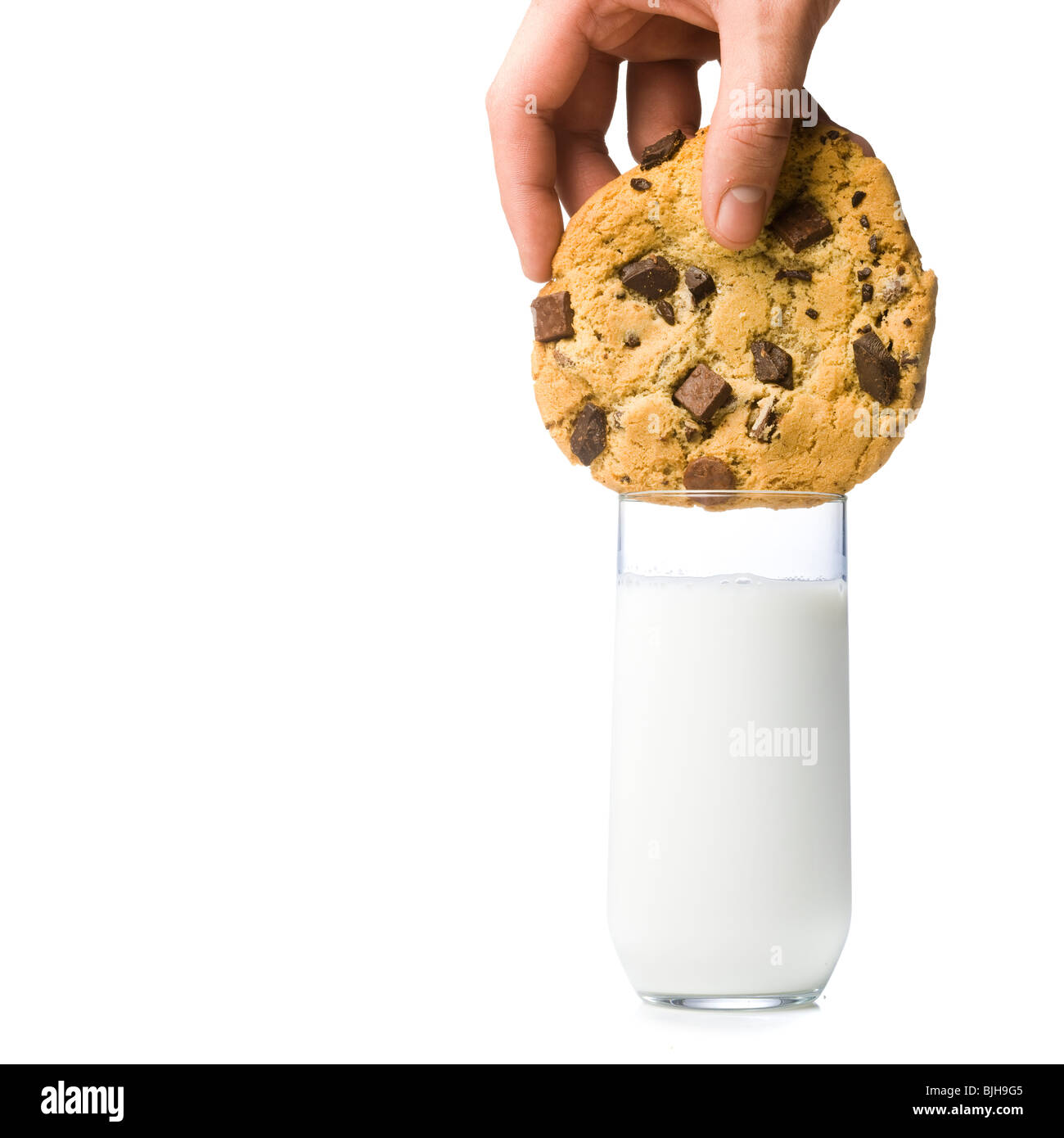 Hand, die versucht, einen Cookie dunk, die in einem Glas Milch zu groß, zu klein ist Stockfoto