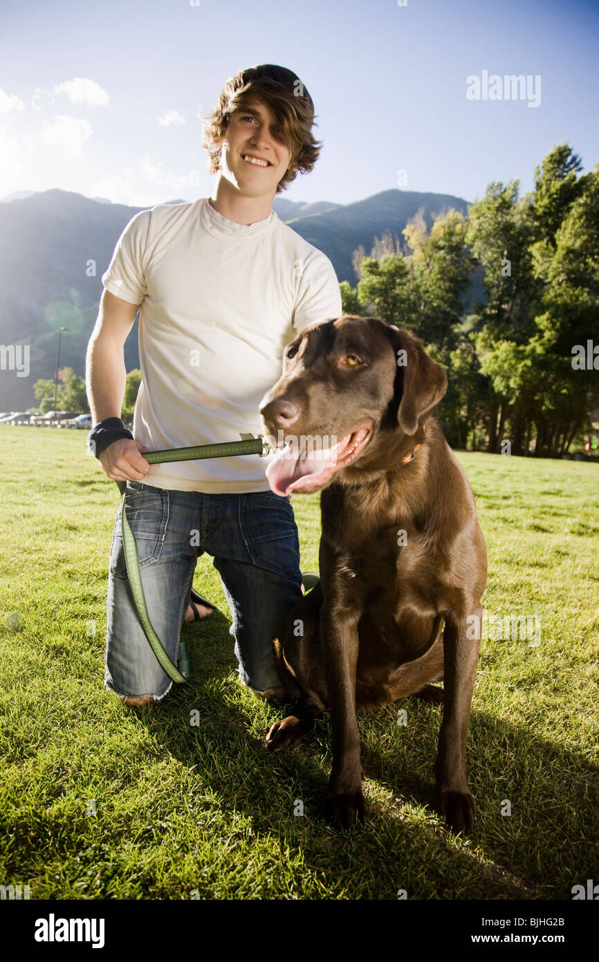 junger Mann kniend mit einem chocolate Labrador retriever Stockfoto