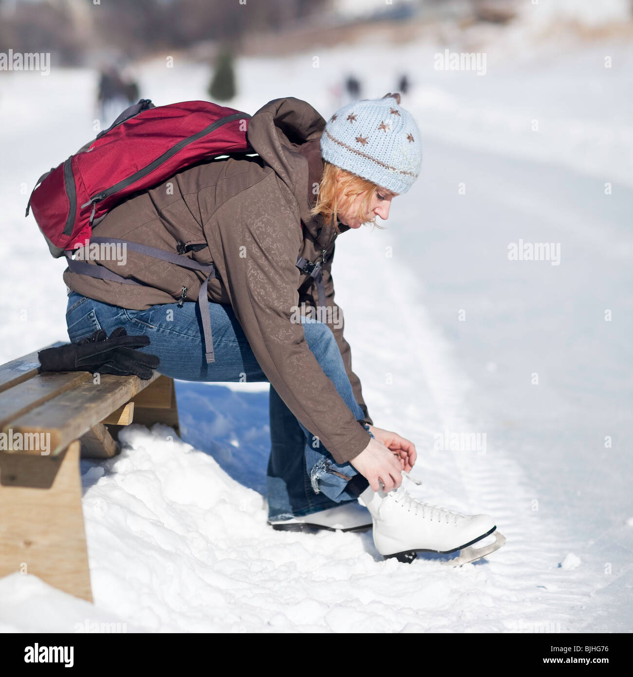 Frau schnürung oben ihre Schlittschuhe im Freien, Assiniboine River Trail, Winnipeg, Manitoba, Kanada. Stockfoto