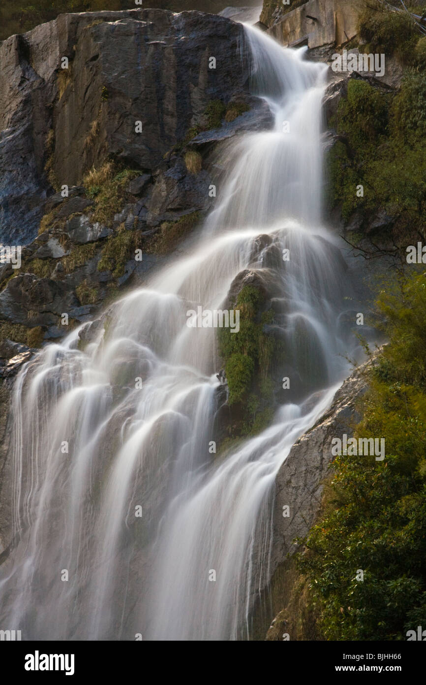 Ein Wasserfall fällt von den steilen Klippen auf der rund um die ANNAPURNA TREK - NUPRI REGION NEPALS Stockfoto
