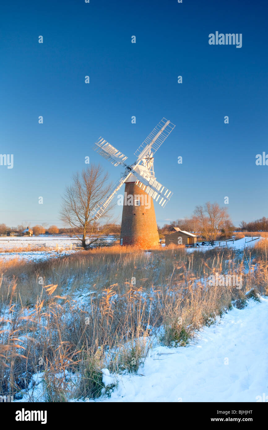 Die schiefen Hardley Entwässerung Mühle an der ersten Ampel nach Winter Schneefall auf den Norfolk Broads Stockfoto