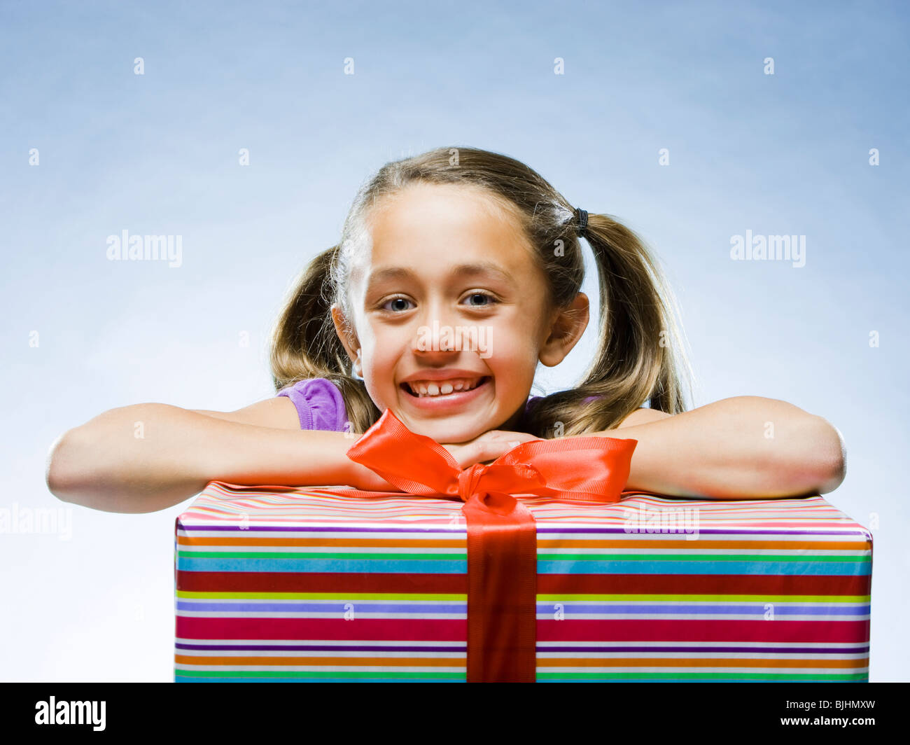 Mädchen schaut in die Kamera ruht ihr Kopf auf ein Geschenk Stockfoto