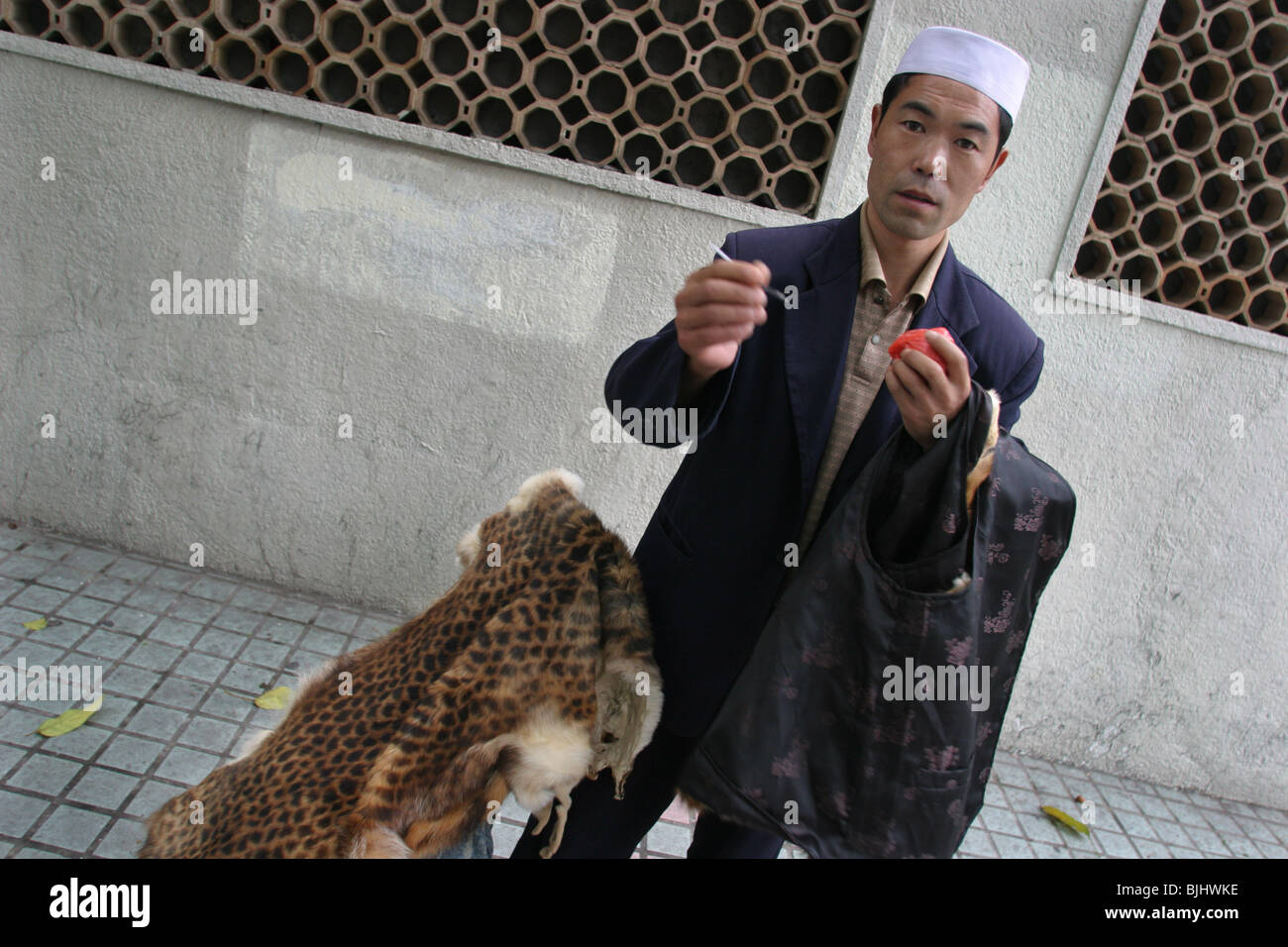 Ein Mann, Tierhäute und Felle, von unbekannten Tieren, auf einer Straße in Guangzhou, südlichen China verkaufen. Stockfoto