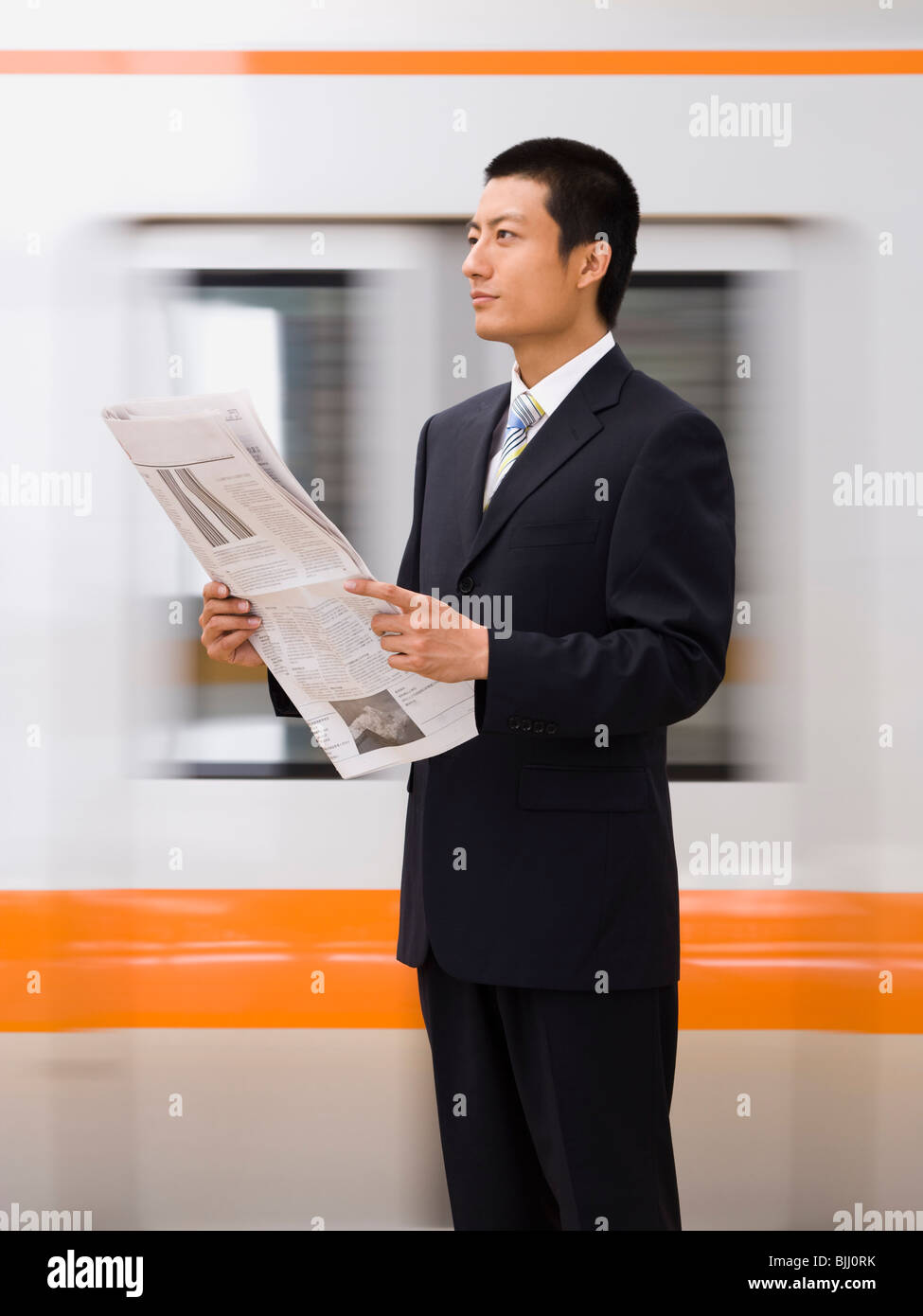 Geschäftsmann, lesen Zeitung mit u-Bahn im Hintergrund Stockfoto