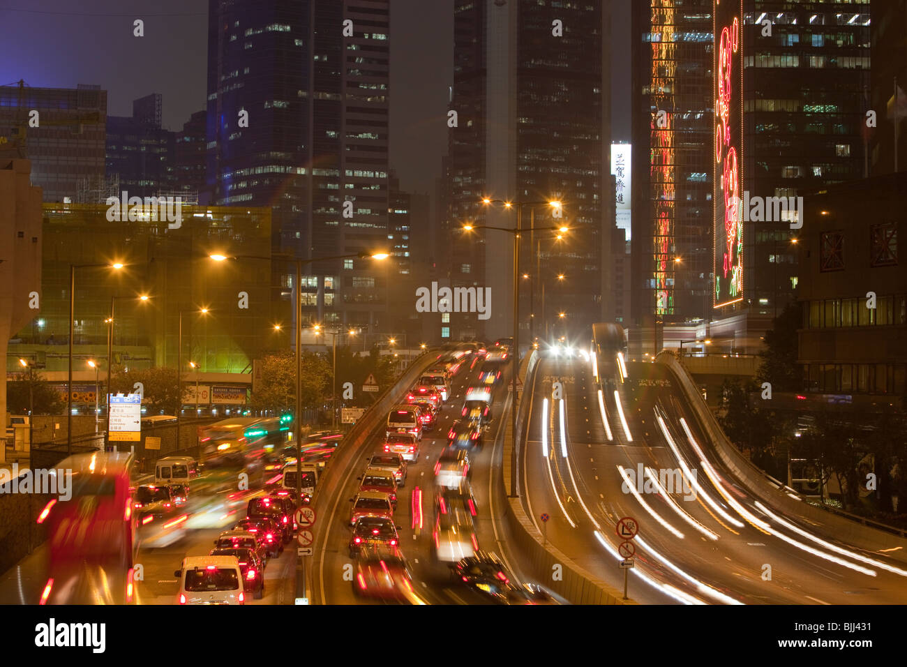 Bürohäuser beleuchtet in der Nacht und Autos in Hong Kong, China. Diese dicht besiedelten Stadt hat einen massiven CO2-Fußabdruck. Stockfoto