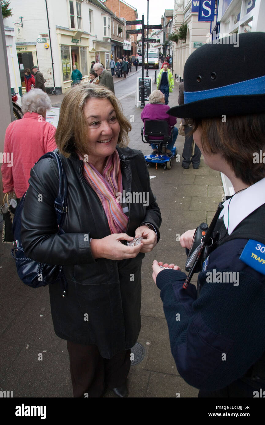 Eine Dame mittleren Alters erläutert Geldbörse Ketten mit einer Community Support Polizistin auf der Einkaufsstraße einer Kleinstadt. Stockfoto