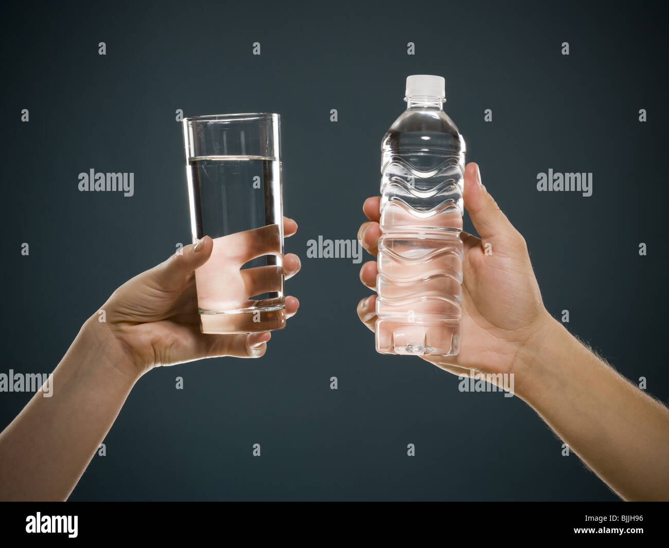 Glas Wasser hält die Hand und hand halten Wasser in Flaschen Stockfoto