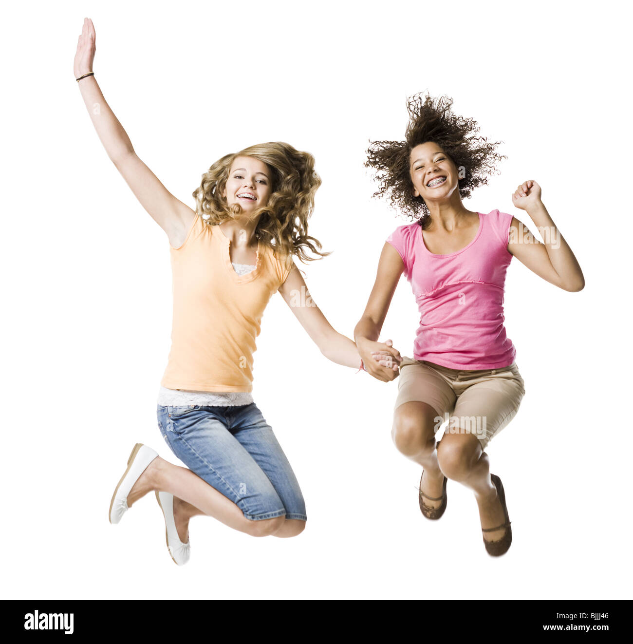 Zwei Mädchen mit Zahnspange Händchenhalten und springen Stockfoto