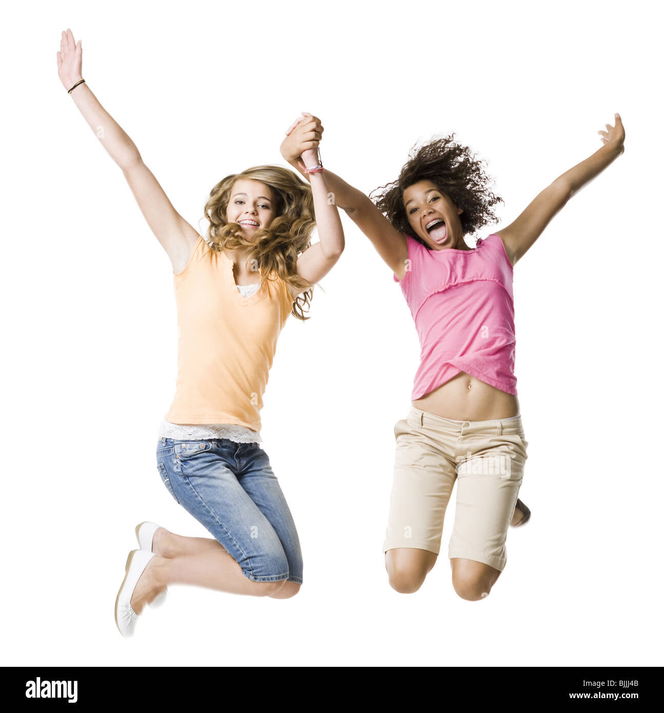 Zwei Mädchen mit Zahnspange Händchenhalten und springen Stockfoto