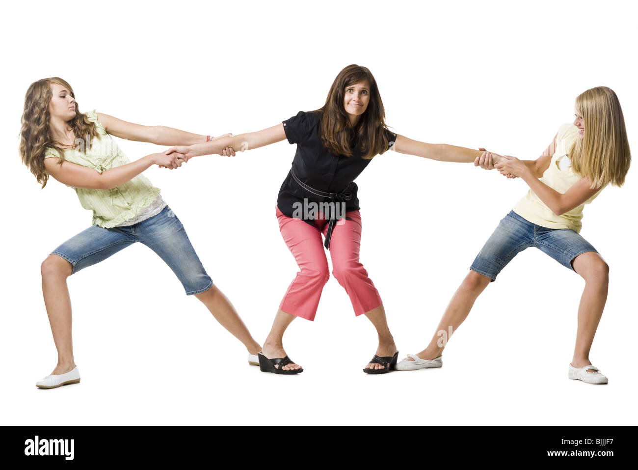 Zwei Mädchen ziehen die arme Mutter in beide Richtungen Stockfotografie
