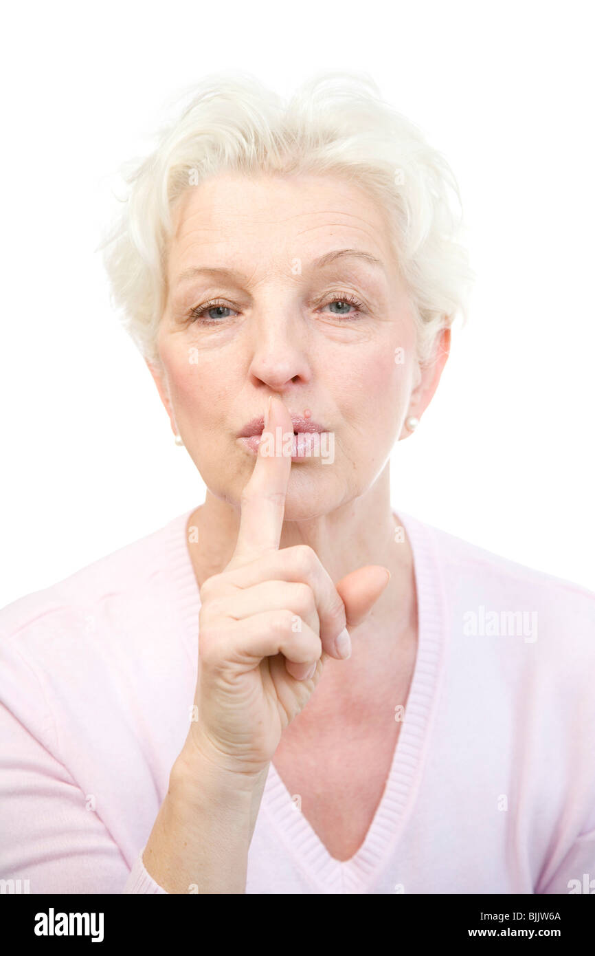 Frau, 60, hält den Finger an die Lippen Stockfoto