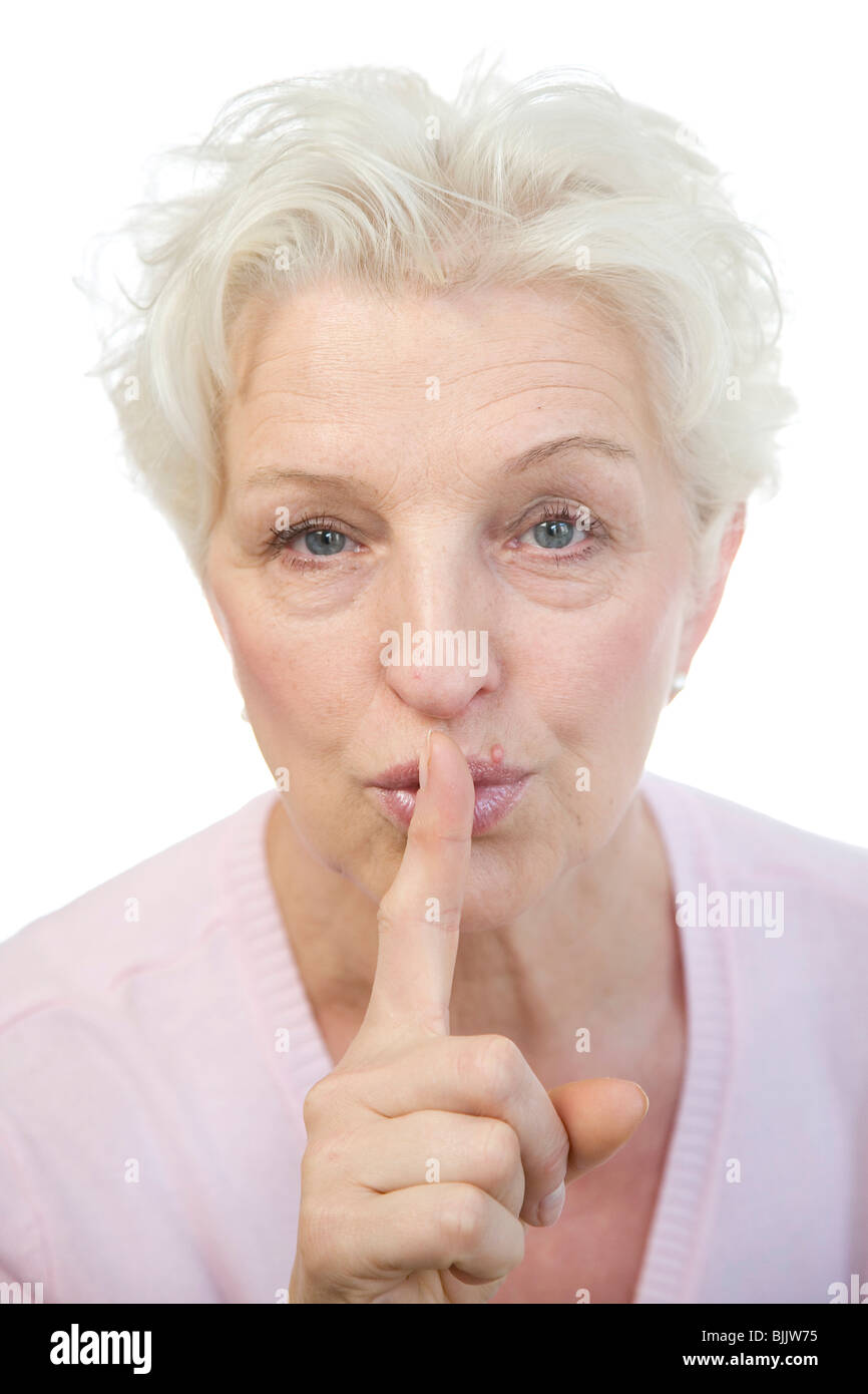 Frau, 60, hält den Finger an die Lippen Stockfoto
