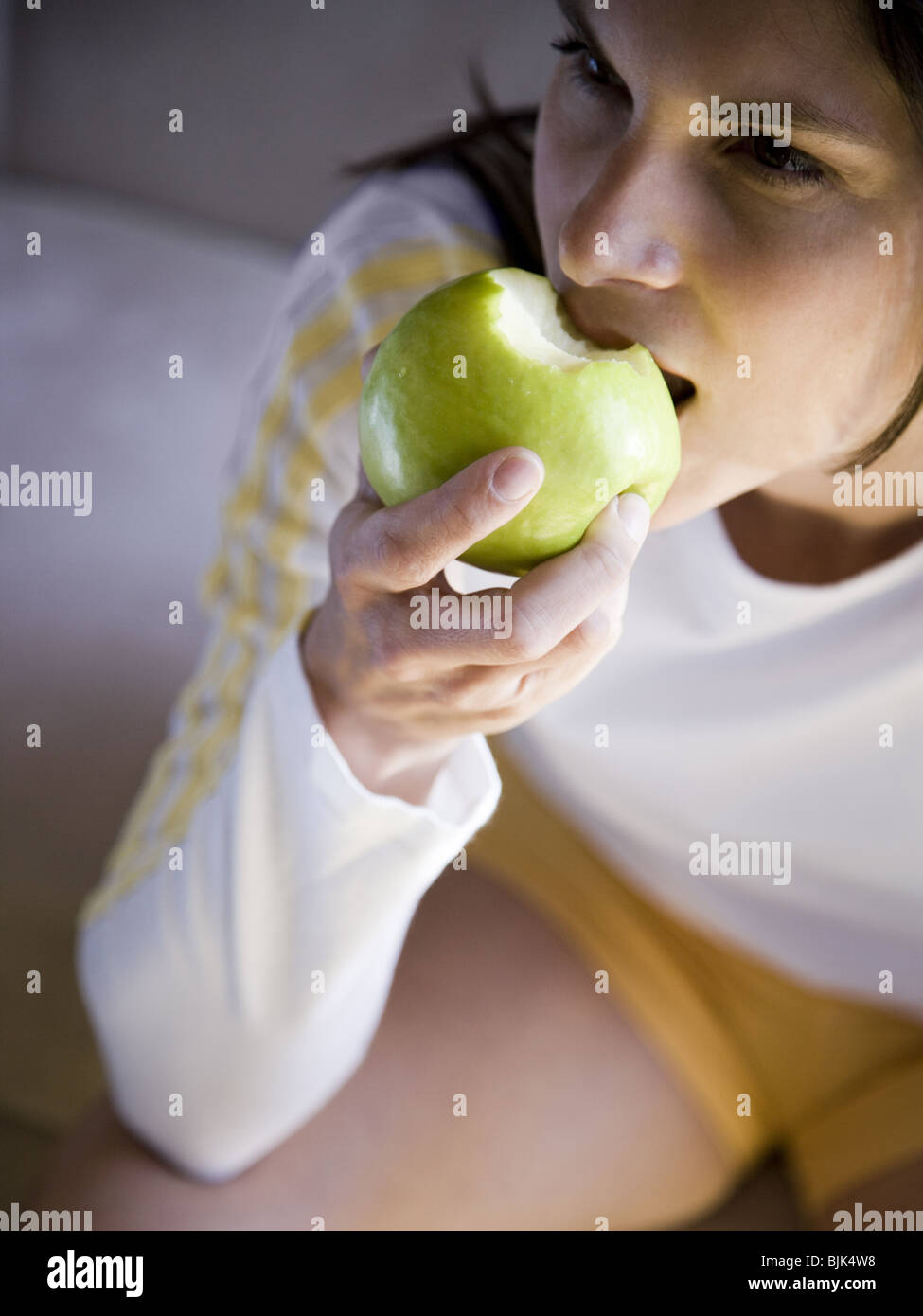 Frau sitzt und grünen Apfel essen Stockfoto